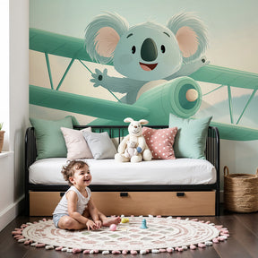 Adventure koala pilot mural wallpaper in modern nursery with natural wood furniture by Kids-Mundo