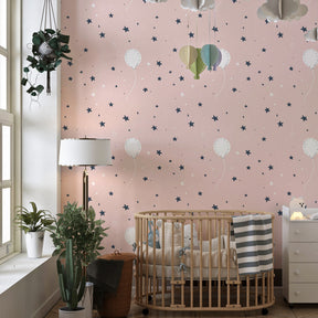 Soft pink balloon wallpaper creating dreamy atmosphere in toddler bedroom with light wood furniture