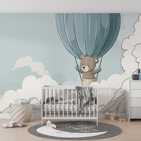 Adventure theme bear wallpaper in cozy baby bedroom with soft blue cloud design