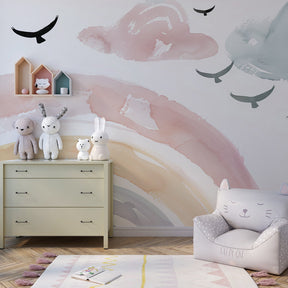Gentle watercolor rainbow wallpaper complementing white nursery furniture and soft decor elements
